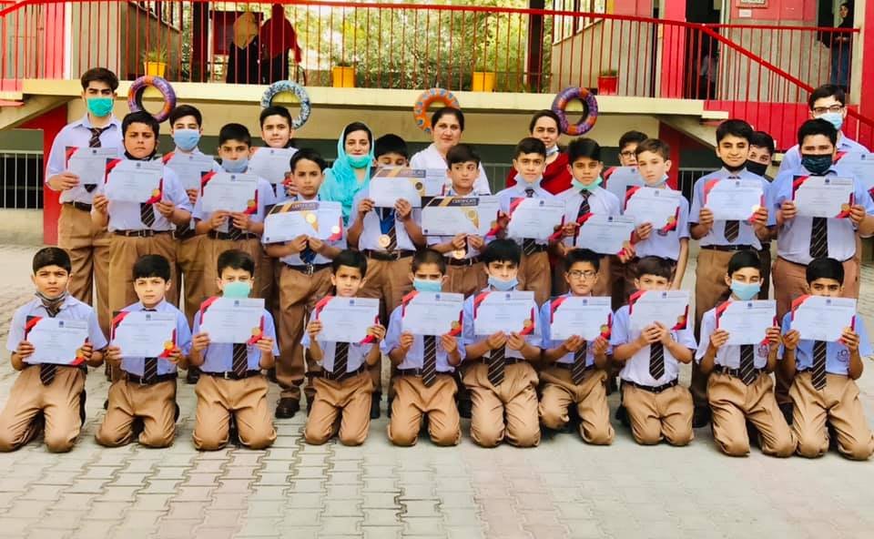Students of Peshawar Model Schools holding certificates with their teachers